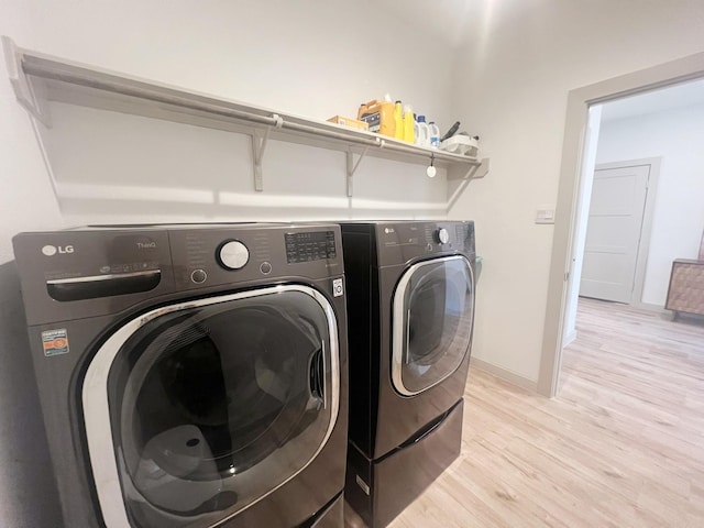 10023 Angelina Woods Ln, Conroe, TX 77384 - laundry room with washing machine and dryer, light wood-style floors, and baseboards