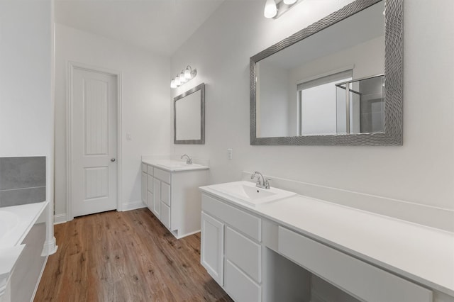 10091 Black Maple Dr, Conroe, TX 77385 - full bathroom with wood finished floors, two vanities, a garden tub, baseboards, and a shower