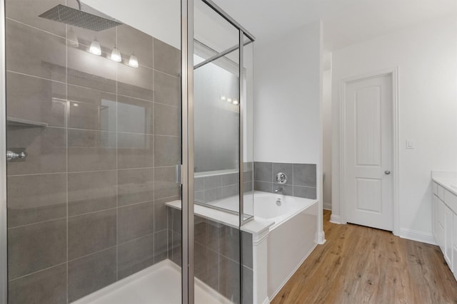 10091 Black Maple Dr, Conroe, TX 77385 - bathroom featuring a shower stall, vanity, a garden tub, wood finished floors, and baseboards
