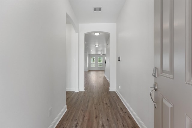 10091 Black Maple Dr, Conroe, TX 77385 - hallway featuring arched walkways, dark wood finished floors, and baseboards
