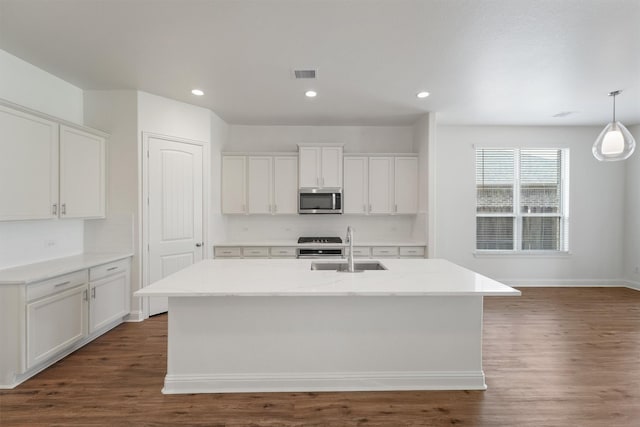 10091 Black Maple Dr, Conroe, TX 77385 - kitchen with a sink, stainless steel microwave, dark wood-type flooring, white cabinetry, and a center island with sink