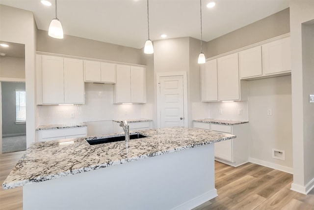 1203 Wildflower Way Dr, Beasley, TX 77417 - kitchen featuring white cabinetry, light wood-type flooring, a kitchen island with sink, light stone countertops, and recessed lighting