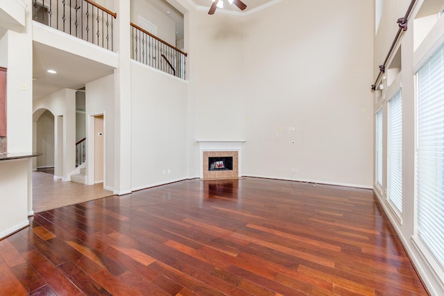 3531 Urban Woods Trl, Houston, TX 77008 - unfurnished living room with a high ceiling, a ceiling fan, arched walkways, hardwood / wood-style floors, and a tile fireplace