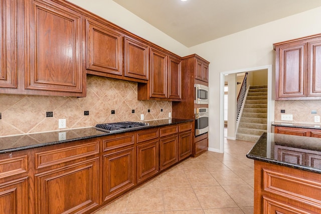 3531 Urban Woods Trl, Houston, TX 77008 - kitchen with appliances with stainless steel finishes, brown cabinetry, dark stone counters, light tile patterned floors, and decorative backsplash