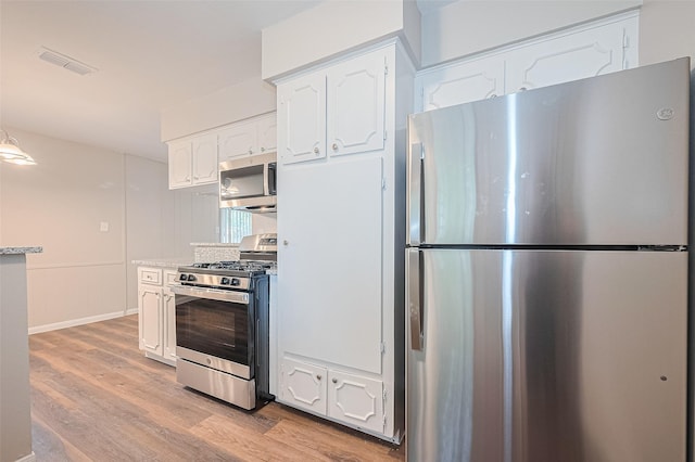 9003 Chateau Forest Dr, Houston, TX 77088 - kitchen featuring stainless steel appliances, white cabinets, light wood-type flooring, and decorative light fixtures
