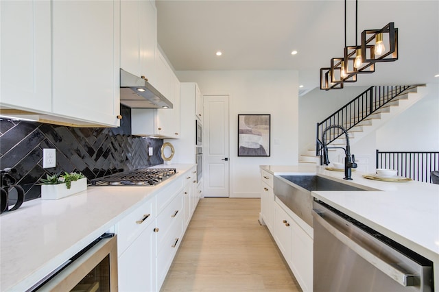2310 Reinerman St, Houston, TX 77007 - kitchen with under cabinet range hood, appliances with stainless steel finishes, beverage cooler, light wood-style flooring, and tasteful backsplash