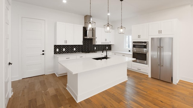 4785 W Fork Blvd, Conroe, TX 77304 - kitchen featuring stainless steel appliances, a sink, decorative backsplash, and wood finished floors