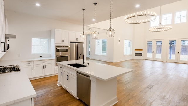 4785 W Fork Blvd, Conroe, TX 77304 - kitchen with a sink, stainless steel appliances, light wood finished floors, light countertops, and a high ceiling