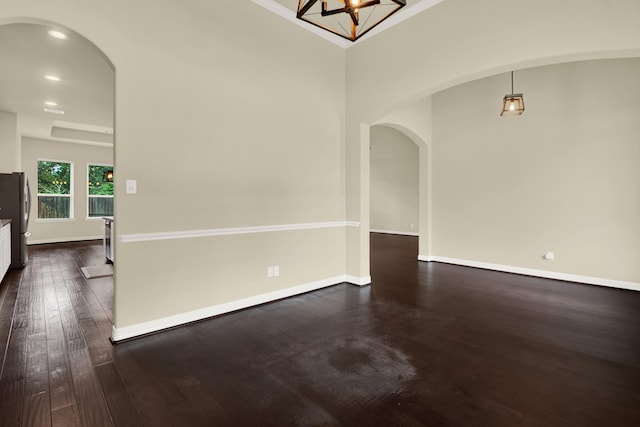 12406 Fort Isabella Ct, Tomball, TX 77375 - empty room with arched walkways, dark wood-type flooring, baseboards, recessed lighting, and a chandelier