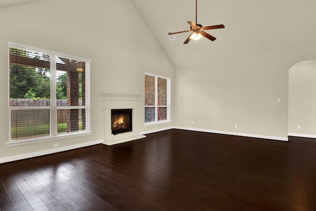 12406 Fort Isabella Ct, Tomball, TX 77375 - unfurnished living room featuring high vaulted ceiling, wood finished floors, arched walkways, a glass covered fireplace, and baseboards