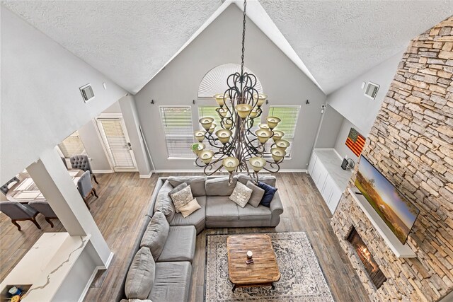 2907 Silverberry Trl, Houston, TX 77345 - living area with a textured ceiling, a chandelier, wood finished floors, a warm lit fireplace, and high vaulted ceiling