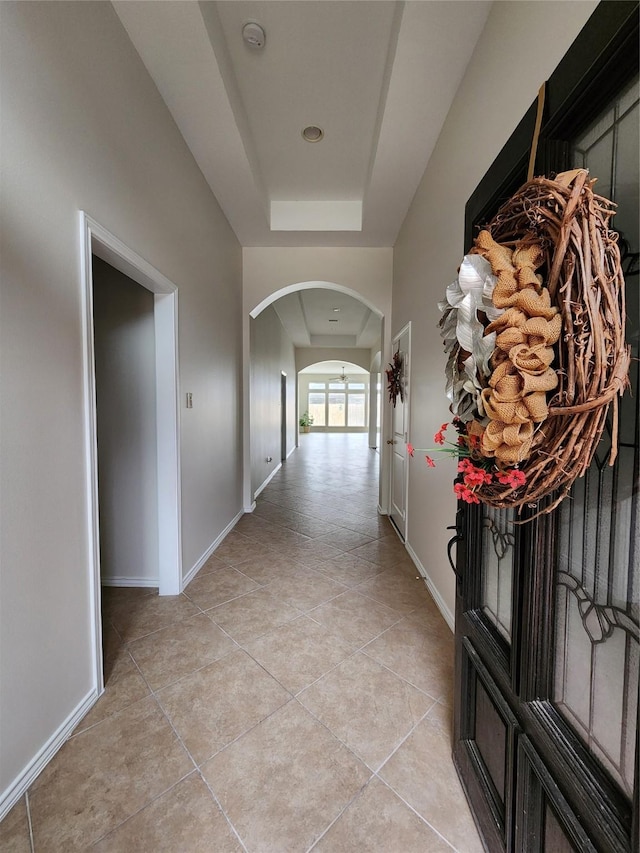 13705 Rainwater Dr, Pearland, TX 77584 - hall featuring arched walkways, light tile patterned floors, baseboards, and a tray ceiling