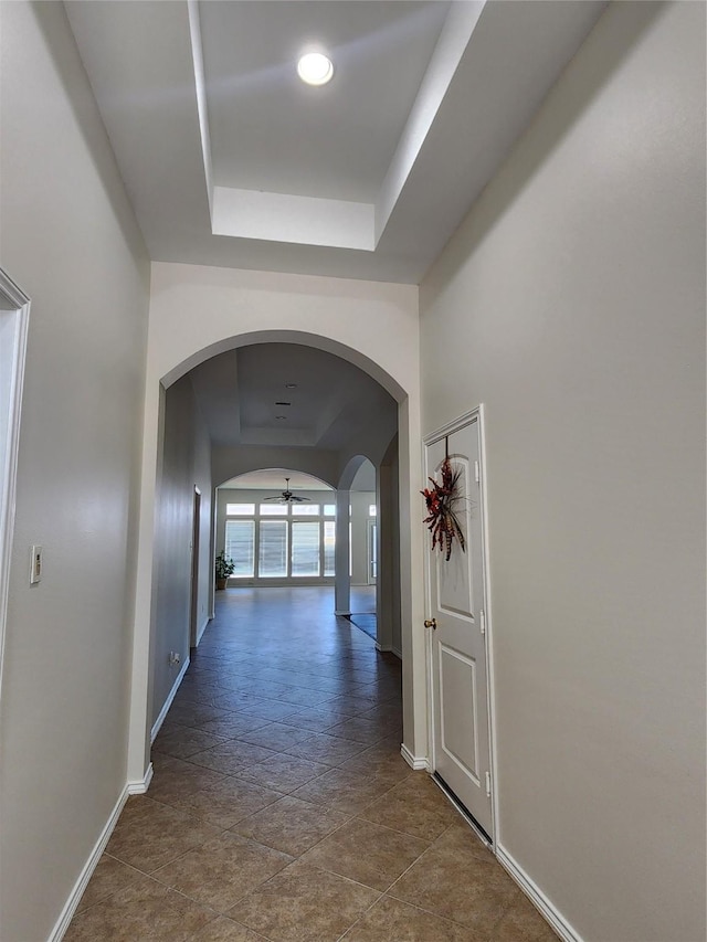 13705 Rainwater Dr, Pearland, TX 77584 - hall featuring a tray ceiling, arched walkways, and baseboards