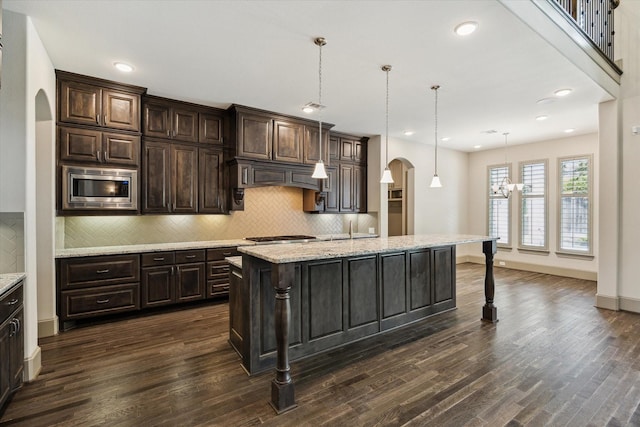 12710 Pebblebrook Dr, Houston, TX 77024 - kitchen with arched walkways, appliances with stainless steel finishes, a breakfast bar area, dark wood-style flooring, and recessed lighting