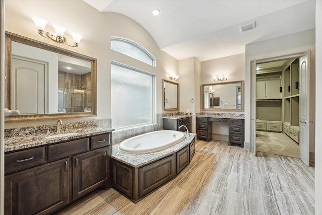 12710 Pebblebrook Dr, Houston, TX 77024 - bathroom with lofted ceiling, a shower stall, two vanities, a garden tub, and wood finished floors