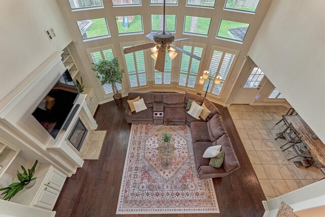 25322 Metzler Creek Dr, Spring, TX 77389 - living room featuring a towering ceiling, ceiling fan, wood finished floors, a premium fireplace, and baseboards