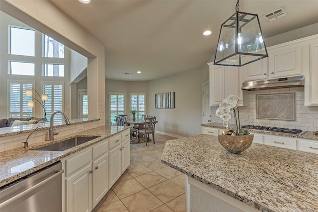 25322 Metzler Creek Dr, Spring, TX 77389 - kitchen with under cabinet range hood, appliances with stainless steel finishes, a sink, tasteful backsplash, and light stone counters