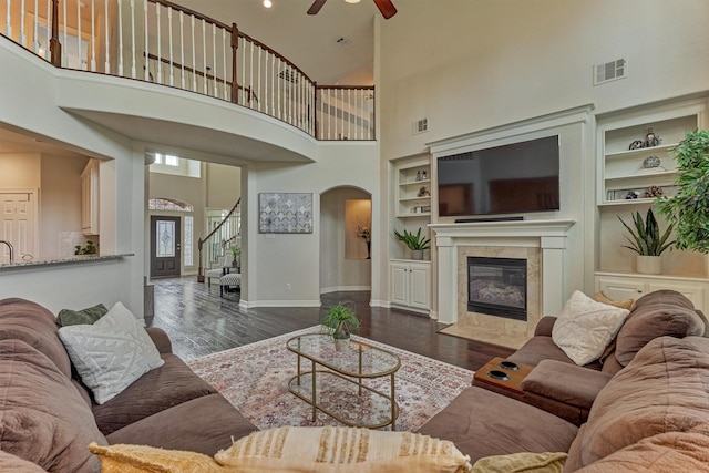 25322 Metzler Creek Dr, Spring, TX 77389 - living room with arched walkways, built in features, a towering ceiling, ceiling fan, and dark wood-type flooring