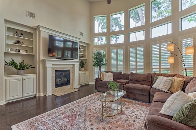 25322 Metzler Creek Dr, Spring, TX 77389 - living area with dark wood-style floors, built in shelves, a high ceiling, a fireplace, and baseboards
