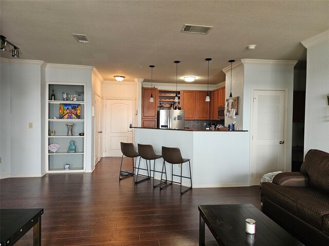 1711 Old Spanish Trl Unit 313, Houston, TX 77054 - kitchen featuring stainless steel appliances, a peninsula, brown cabinetry, dark countertops, and dark wood-type flooring