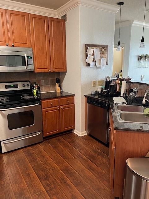 1711 Old Spanish Trl Unit 313, Houston, TX 77054 - kitchen with appliances with stainless steel finishes, crown molding, a sink, brown cabinets, and dark wood finished floors
