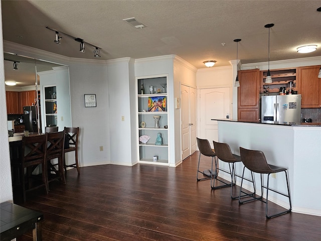 1711 Old Spanish Trl Unit 313, Houston, TX 77054 - kitchen featuring stainless steel fridge with ice dispenser, black refrigerator with ice dispenser, brown cabinetry, a kitchen breakfast bar, and a textured ceiling