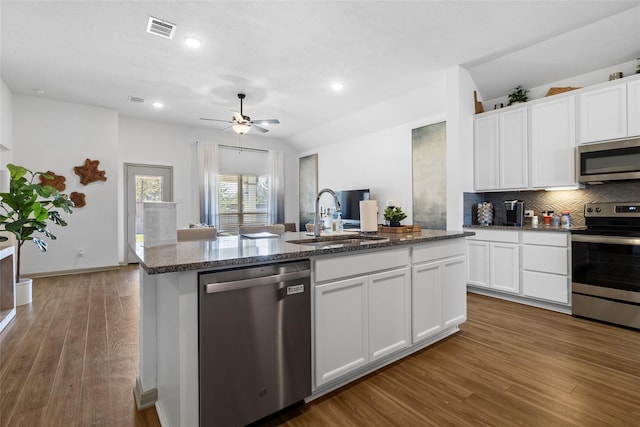 204 Shoreview Dr, Conroe, TX 77303 - kitchen with appliances with stainless steel finishes, a center island with sink, backsplash, wood finished floors, and white cabinets
