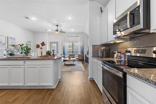 204 Shoreview Dr, Conroe, TX 77303 - kitchen with appliances with stainless steel finishes, wood finished floors, white cabinetry, decorative backsplash, and recessed lighting
