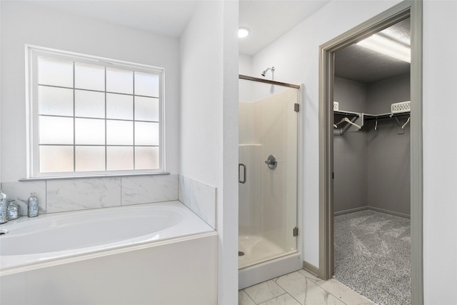 204 Shoreview Dr, Conroe, TX 77303 - full bathroom featuring a stall shower, a bath, a walk in closet, marble look tiles, and baseboards