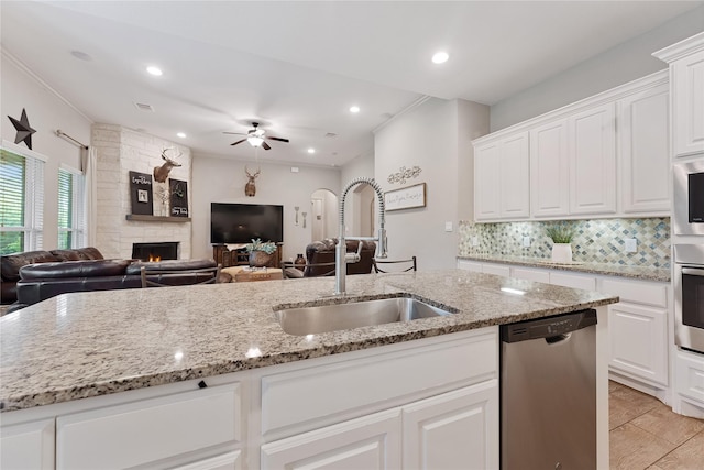 28026 Chuckwagon Trl, Magnolia, TX 77355 - kitchen with appliances with stainless steel finishes, a sink, open floor plan, a ceiling fan, and a fireplace