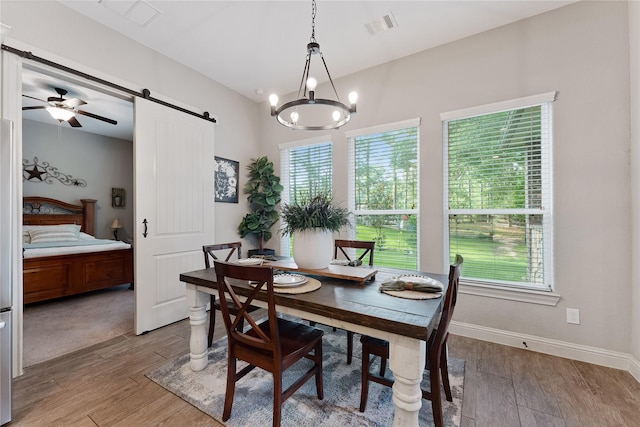 28026 Chuckwagon Trl, Magnolia, TX 77355 - dining space featuring a barn door, light wood-style flooring, a chandelier, baseboards, and a ceiling fan