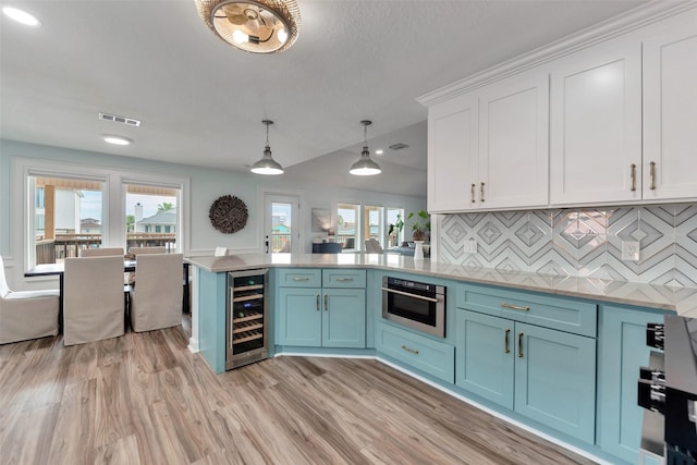 1427 Bamboo Dr, Tiki Island, TX 77554 - kitchen featuring beverage cooler, blue cabinets, white cabinetry, oven, and a peninsula