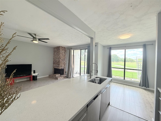 8149 Sands Point Dr Unit 113, Houston, TX 77036 - kitchen with a sink, stainless steel dishwasher, open floor plan, a textured ceiling, and light wood-style flooring