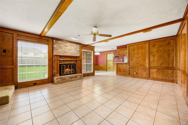 4923 Bradstone Ct, Houston, TX 77084 - unfurnished living room featuring a ceiling fan, a textured ceiling, wood walls, a brick fireplace, and light tile patterned floors