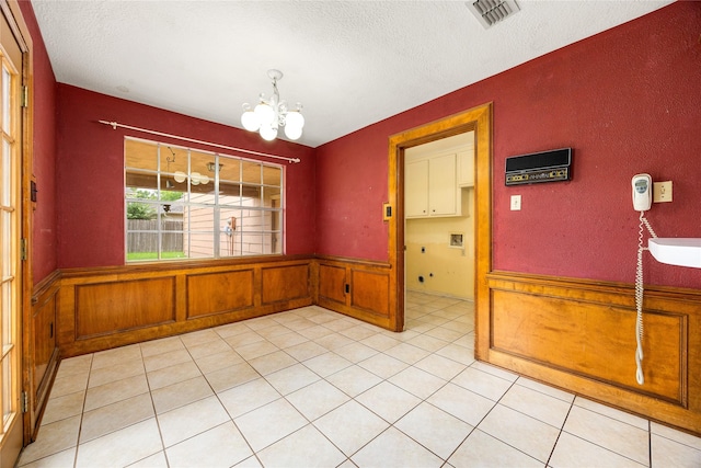 4923 Bradstone Ct, Houston, TX 77084 - unfurnished dining area featuring a chandelier, a textured ceiling, wainscoting, and light tile patterned floors