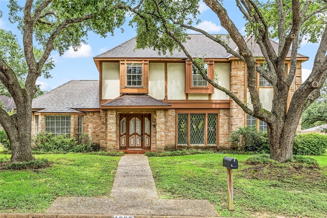 4923 Bradstone Ct, Houston, TX 77084 - tudor house with a front yard, a shingled roof, stucco siding, and brick siding