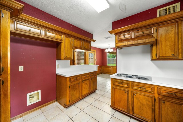 4923 Bradstone Ct, Houston, TX 77084 - kitchen with light countertops, electric cooktop, brown cabinetry, a textured ceiling, and light tile patterned floors