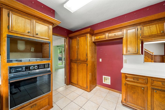 4923 Bradstone Ct, Houston, TX 77084 - kitchen with black oven, brown cabinetry, light countertops, light tile patterned floors, and a textured ceiling