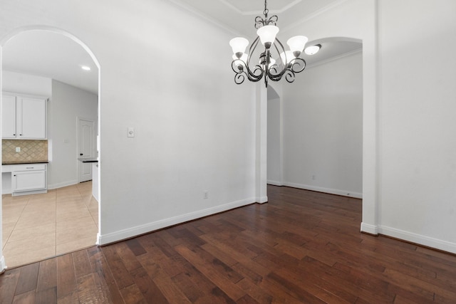 7 Fraiser Fir Pl, Spring, TX 77389 - unfurnished dining area featuring arched walkways, a chandelier, ornamental molding, hardwood / wood-style floors, and baseboards