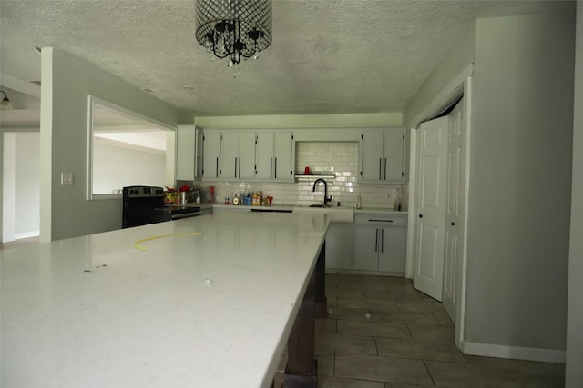 5952 Moonstone St, Port Arthur, TX 77640 - kitchen with a sink, stainless steel range with electric stovetop, light countertops, a textured ceiling, and decorative backsplash
