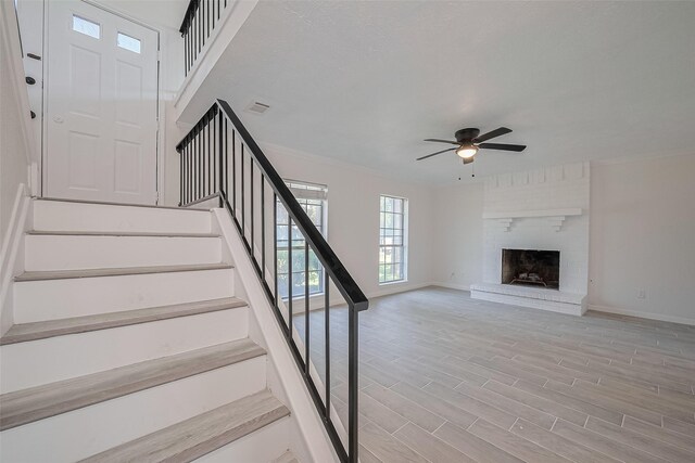 413 E Castle Harbour Dr W, Friendswood, TX 77546 - stairs featuring a ceiling fan, baseboards, crown molding, wood finished floors, and a brick fireplace