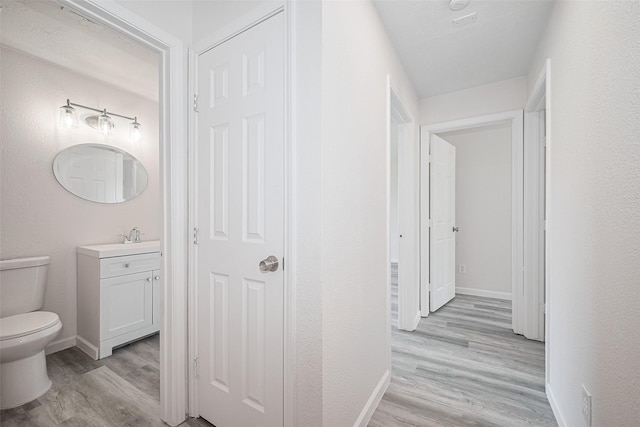 413 E Castle Harbour Dr W, Friendswood, TX 77546 - hallway with light wood-style flooring, baseboards, and a sink