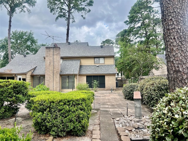 6523 Coral Ridge Rd, Houston, TX 77069 - view of front of home with roof with shingles, brick siding, a patio area, and a chimney