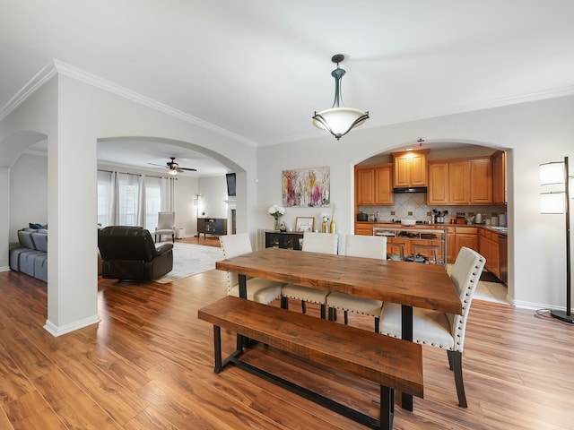 7106 Harmony Cv, Houston, TX 77036 - dining space with arched walkways, ornamental molding, light wood-type flooring, ceiling fan, and baseboards