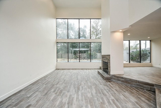8115 Fondren Lake Dr, Houston, TX 77071 - unfurnished living room with a towering ceiling, wood finished floors, a glass covered fireplace, baseboards, and recessed lighting