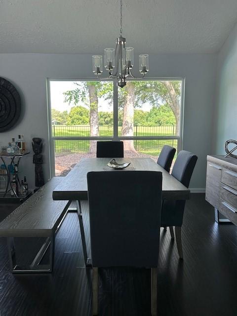 3311 Oyster Cove Dr, Missouri City, TX 77459 - dining area with dark wood-style flooring, a chandelier, a textured ceiling, and baseboards