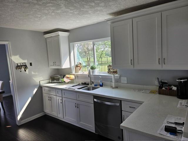 3311 Oyster Cove Dr, Missouri City, TX 77459 - kitchen with dishwasher, a sink, light countertops, a textured ceiling, and white cabinets