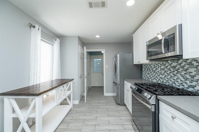 15923 Pine Mountain Dr, Houston, TX 77084 - kitchen with stainless steel appliances, backsplash, white cabinets, baseboards, and recessed lighting