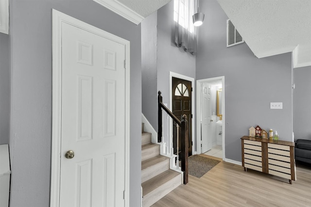 21406 Park Post Ln, Katy, TX 77450 - entrance foyer featuring light wood-style flooring, stairs, a textured ceiling, crown molding, and baseboards