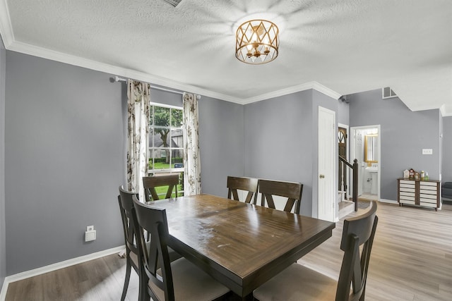 21406 Park Post Ln, Katy, TX 77450 - dining area featuring light wood-style floors, crown molding, a chandelier, a textured ceiling, and baseboards